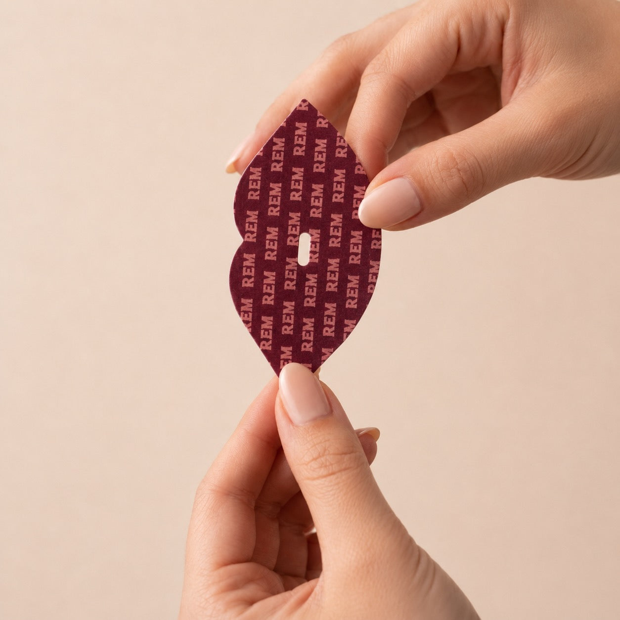 Two hands holding REM Sleep Tape mouth tape showing lip-shaped collagen strip